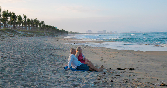 Mature couple relax on beach together at sunset