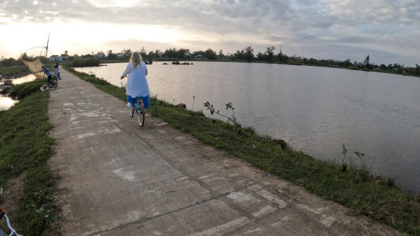 istock Mature woman rides bicycle through rice paddies 1945733004