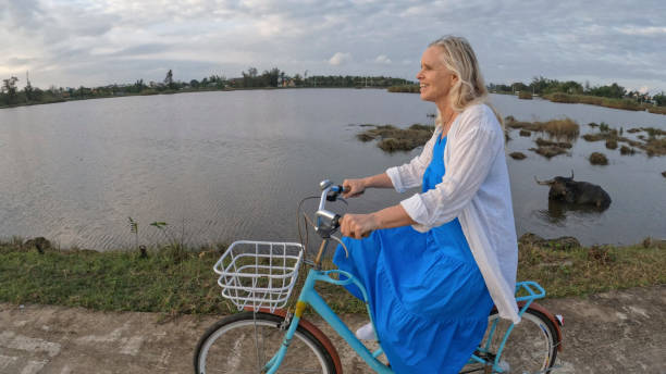 istock Mature woman rides bicycle through rice paddies 1945733005