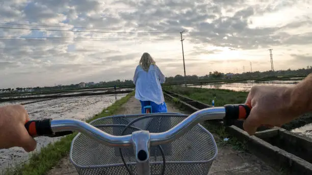 Photo of Mature couple ride bicycles through rice paddies