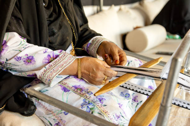 istock Senior Emirati woman using traditional weaving machine, hands in frame 1945734565