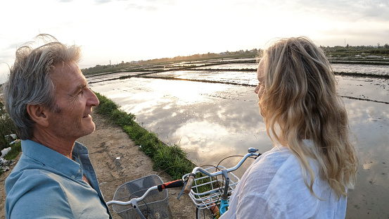 Mature couple pause in rice paddies with bicycles