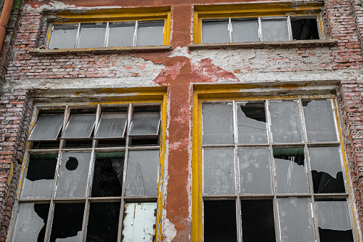 A wall of red tiles was built inside the window. The exterior paint of the house made of adobe has peeled off. the walls are cracked. The windows and walls of the old house were shot in daylight with a full frame camera.