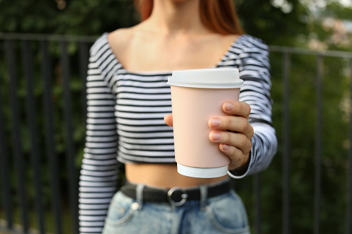 Coffee to go. Woman with paper cup of drink outdoors, selective focus