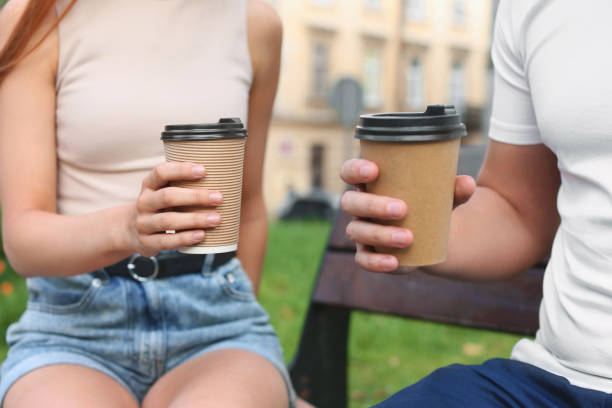 istock Coffee to go. Couple with paper cups outdoors, closeup 1945801037