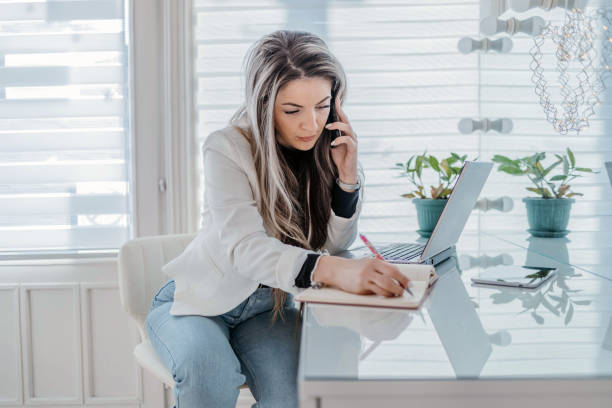 istock Businesswoman talking on the phone and writing down words in a notebook. 1945810928