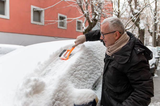 istock A mature man cleaning snow from car windshield outdoors on winter day. 1945813555