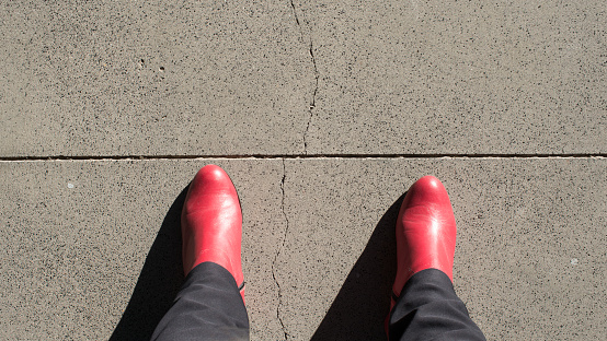 Woman wearing red boots, seen from above, about to cross a line