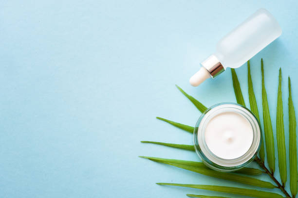 istock Cream jar with palm leaf on blue background. 1945850250