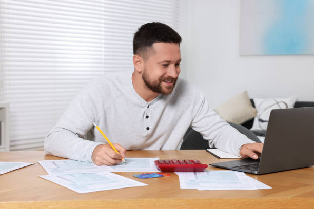 istock Man doing taxes at table in room 1945875656