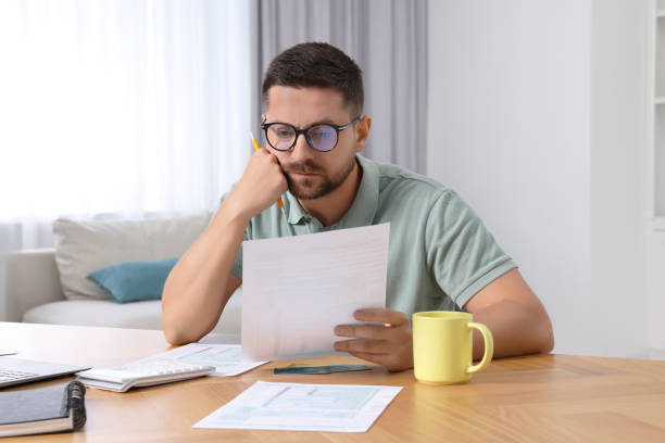 istock Man doing taxes at table in room 1945876741