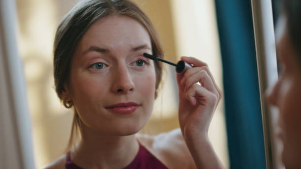 istock Closeup girl using mascara applying on eyelashes. Woman reflection in mirror 1945883582