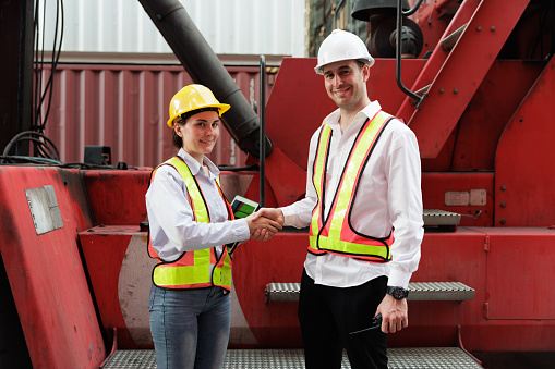 Businessman and woman worker working in container terminal. Making shake hand together after processes