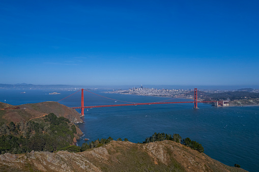 Capture the breathtaking beauty of the iconic Golden Gate Bridge as seen from the top of a hill, surrounded by stunning natural scenery.