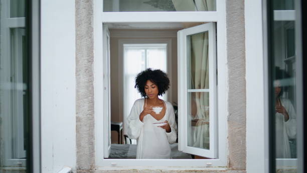 istock Relaxed woman enjoying espresso cup window frame. African lady rest with coffee 1945915914