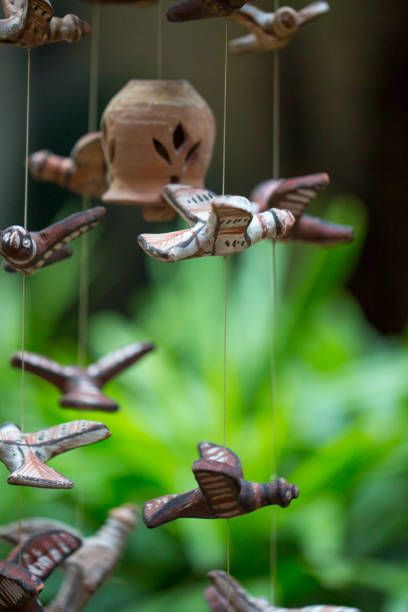 Birds made with clay and painted for a hanging by a potter in front of a lush green foliage stock photo