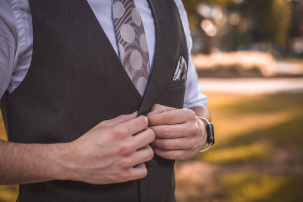Close up of detail on formal suit with orange vest and tie.  Lily flower corsage on lapel.  