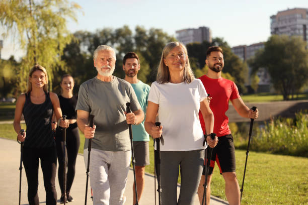 istock Group of happy people practicing Nordic walking with poles in park 1945930100
