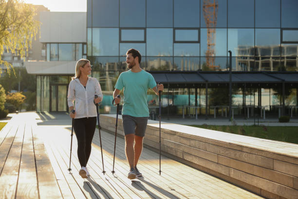 istock Happy couple practicing Nordic walking with poles outdoors 1945931145