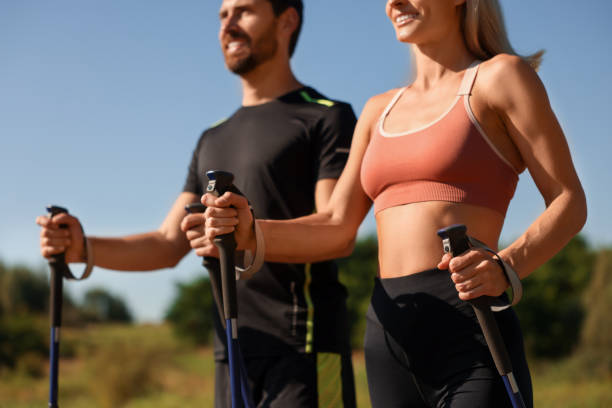 istock Couple practicing Nordic walking with poles outdoors on sunny day, selective focus 1945931160
