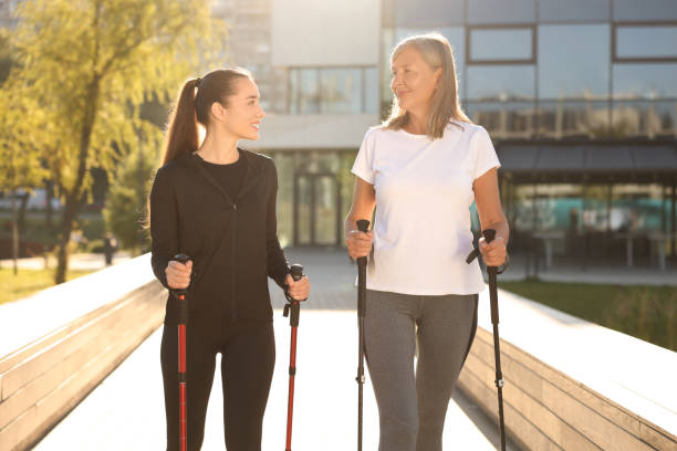 istock Happy women practicing Nordic walking with poles outdoors on sunny day 1945932189