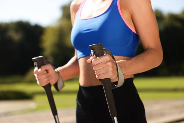 istock Woman practicing Nordic walking with poles outdoors on sunny day, closeup 1945933740