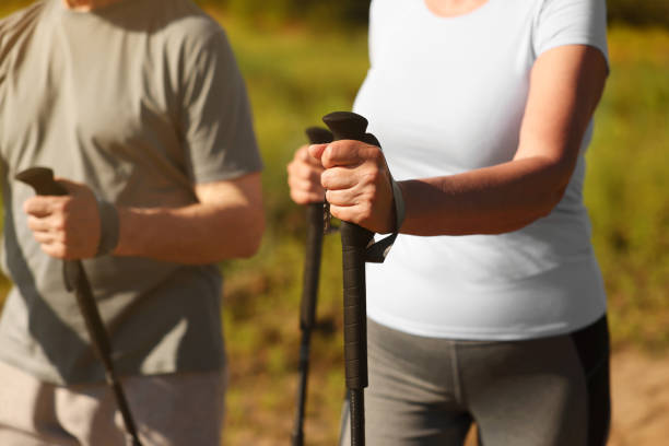 istock Couple practicing Nordic walking with poles outdoors on sunny day, closeup 1945934254