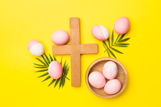 istock Pink Easter eggs with cross and palm leaves on color background, top view 1945959661