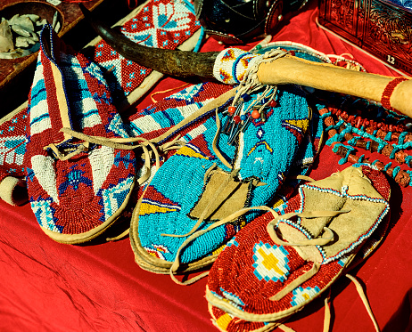 Hand beaded Native American moccasins are on display. Moccasins are considered sacred and are passed down through generations. Unique and tribal designs created for these creations are beautiful.