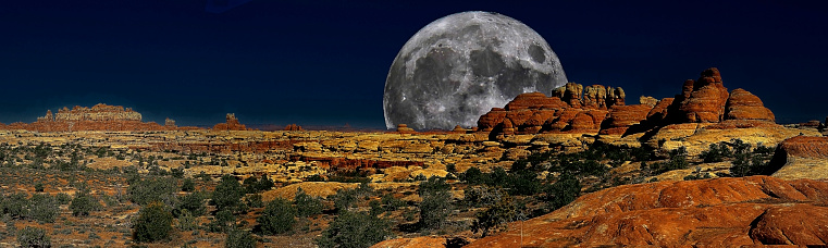 The expansive panoramic view in the Canyon Lands National Park captures the dark sky with the super full moon iluminating the arid desert landscape.