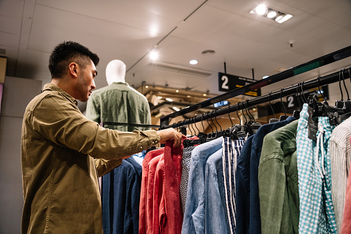 A man browses through shirts, ties, jackets in a retail environment.