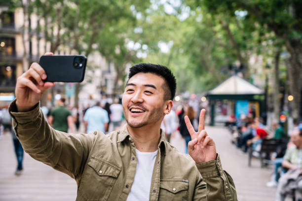 istock Man Making Peace Sign While Taking a Selfie in Urban Park 1945974551