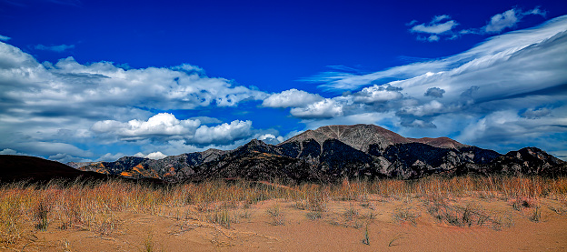 The tallest sand dunes in North America are on display at The Great Sand Dunes - National Park. The deep blue sky seems to hover over the peak of the mountain range of Sangre de Cristo Mountains.