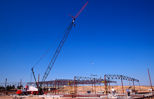 A crane is setting up steel walls for new construction for a strip mall in Albuquerque, NM.