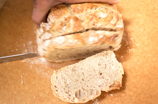 Hands and Knife Cutting Homemade Bread