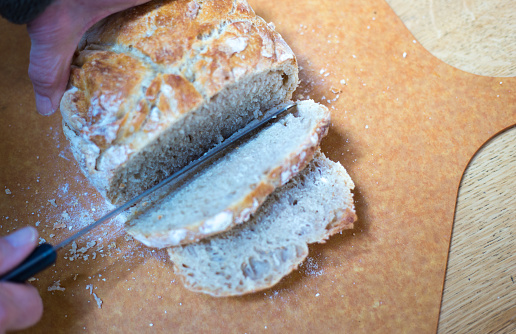 Whole and sliced fresh traditional french baguette bread on wooden table