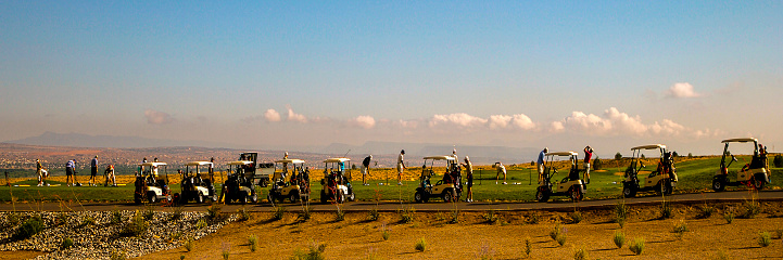Golfers and golf carts line up at the practice tees to loosen up before hitting the greens. A beautiful morning awaits them on the course.