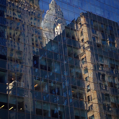 This photograph captures the reflection of the Chrysler Building, an iconic New York City skyscraper, in the glass facade of a nearby office building