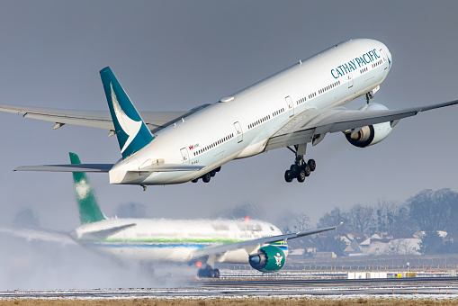 Cathay Pacific Boeing 777-300 taking off from Paris Roissy Charles de Gaulle airporton a snowy day. Registration B-KQJ
