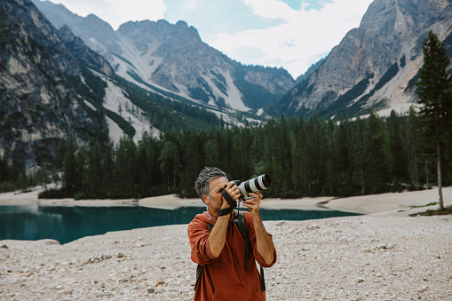 Photographer traveling the Italian Alps, taking beautiful photos next to the Lago di Braies in Dolomites.
