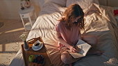Pensive woman writing diary at home. Relaxed teenager dreaming sharing creative