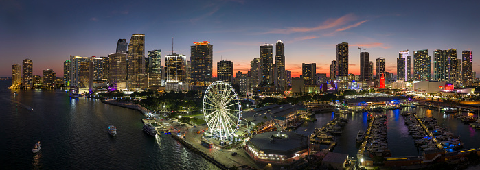 Miami marina harbor and skyscrapers of Brickell, city financial center. Skyviews Miami Observation Wheel at Bayside Marketplace with reflections in Biscayne Bay water and US urban landscape at night.