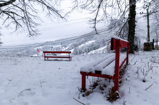 Red bench under snow in Dardhe village, Korça