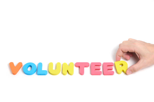 istock Man hand composes word volunteer from multicolored letters white background. 1946263763