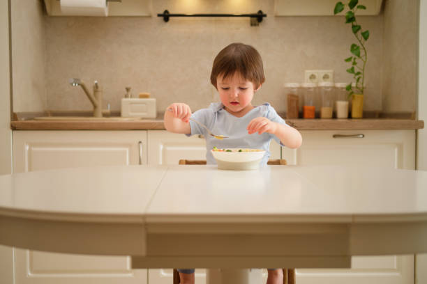 istock A child eats pasta with a fork while sitting at a table in a home kitchen. Cute little boy having breakfast in the kitchen at home. Toddler baby two years old at dinner 1946264917