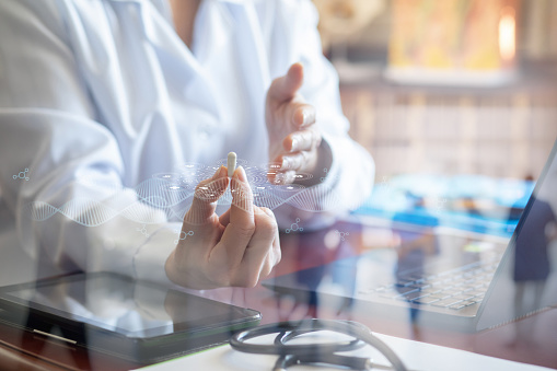 The doctor shows medicine in the form of a pill at the table in the office.