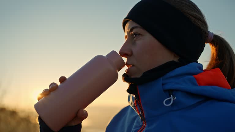 SLO MO Closeup of Young Woman in Warm Clothes Drinking Coffee from Thermos Bottle during Sunrise in Winter