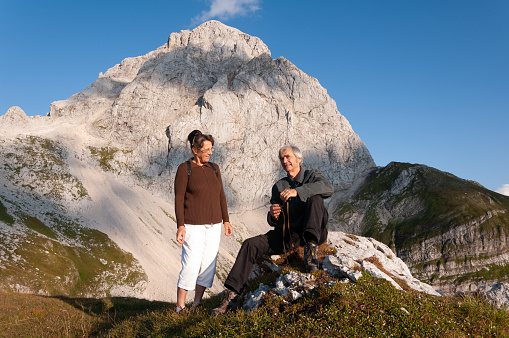 Senior Married Retired Caucasian Couple Hiking in Mountains - Taking a Break - Moment of Relax