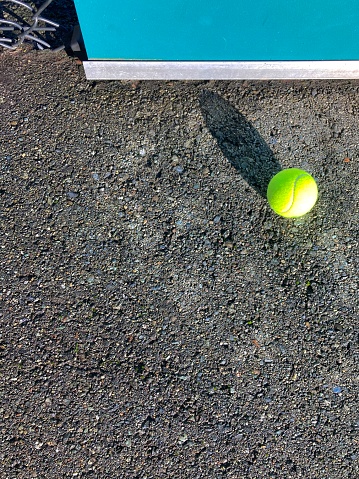 Tennis ball on drying concrete tennis court.