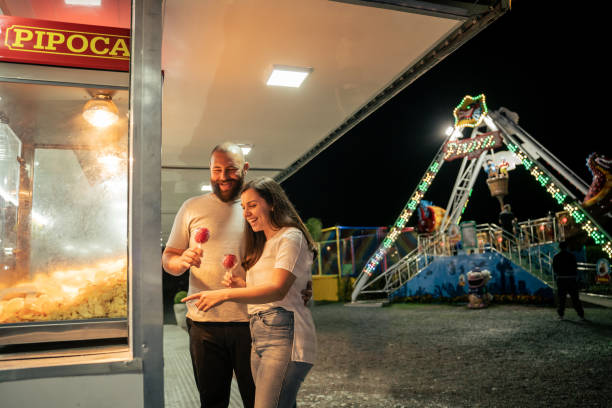 istock Young couple walking through amusement park at night 1946378188